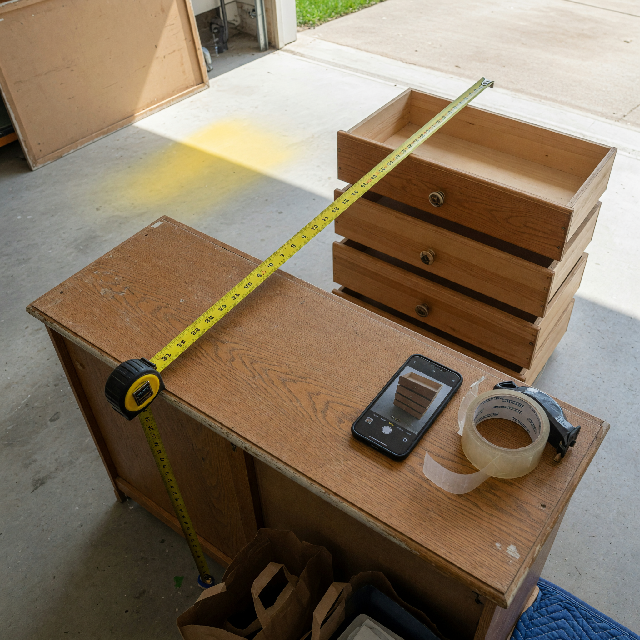 Tape measure across a dresser with drawers removed while a phone is ready for free furniture listing photos